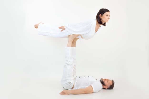 Man and woman couple doing sports exercises fitness and yoga male holding female on legs practicing