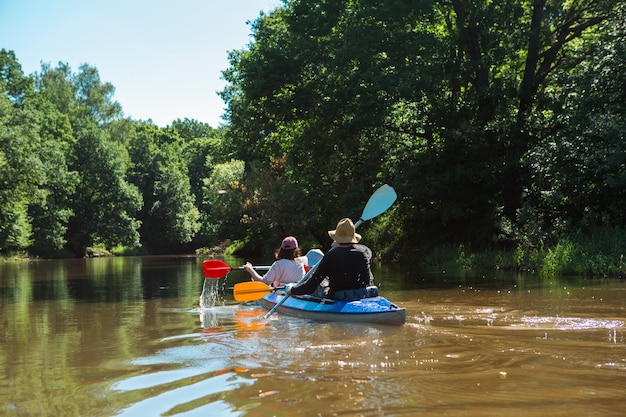 Man and woman couple in family kayak trip rowing boat on the river a water hike a summer adventure Ecofriendly and extreme tourism active and healthy lifestyle