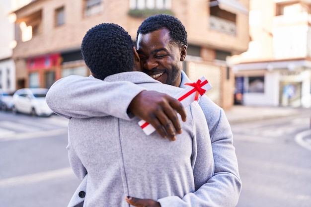 Man and woman couple hugging each other surprise with gift at street