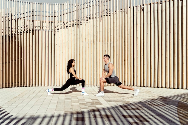 Man and woman couple wearing sportswear stretching at stree