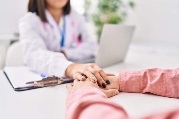 Man and woman doctor and patient having medical consultation with hands together at clinic