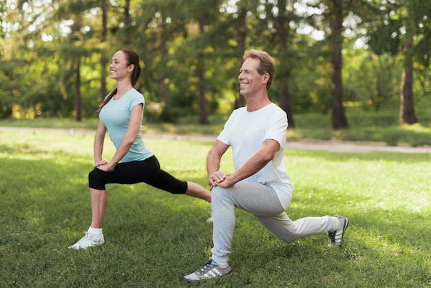 Man and woman doing warm-up in nature.