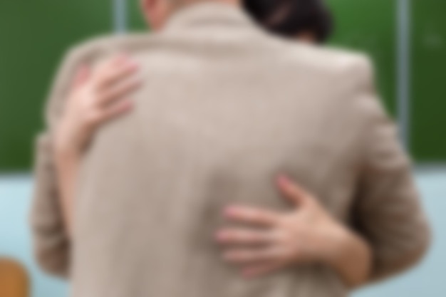 A man and a woman embrace in a school classroom at the blackboard