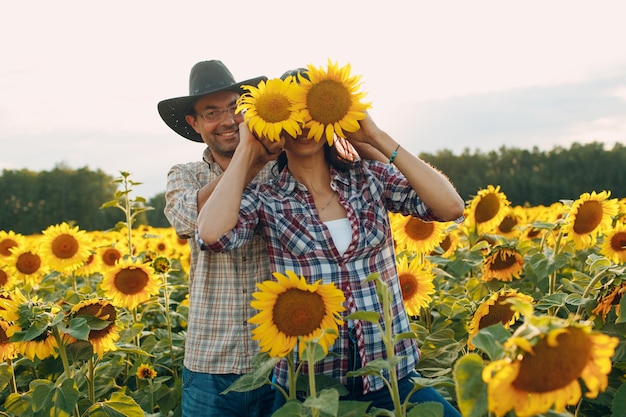 Man and woman farmers at sunflower field checking harvest.