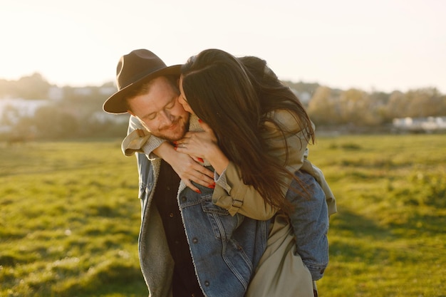 Man and woman in fashion clothes resting on a nature together in sunset