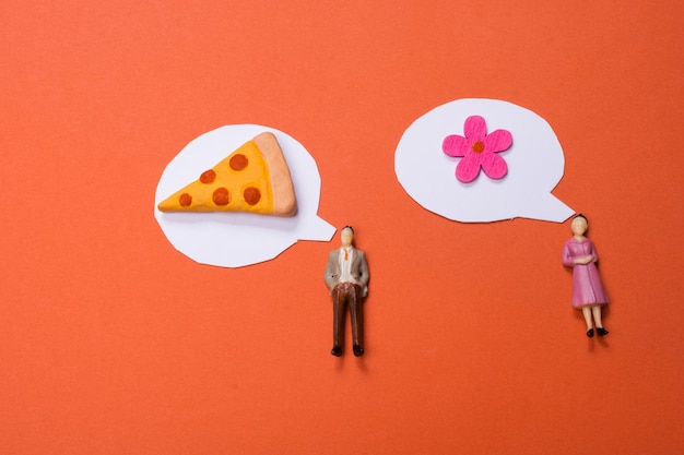 Man and Woman figurine fake flower piece of pizza and Mini speech bubbles cut out of paper