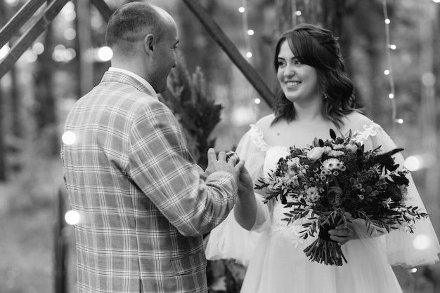 Man and woman got engaged in autumn forest at wedding decorated ceremony