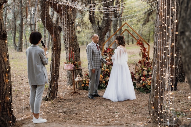 Man and woman got engaged in autumn forest at wedding decorated ceremony