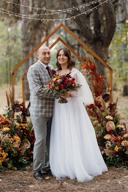 Man and woman got engaged in autumn forest at wedding decorated ceremony