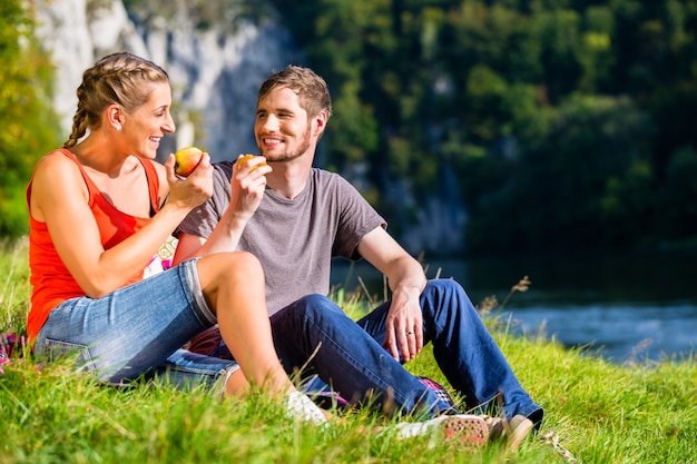 Man and woman having break hiking at river