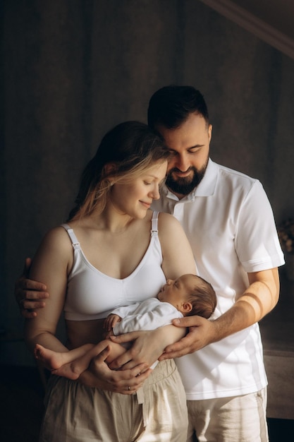 a man and a woman holding a baby and the baby is wearing a white tank top