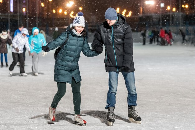 Man and woman holding hands on the rink in the evening