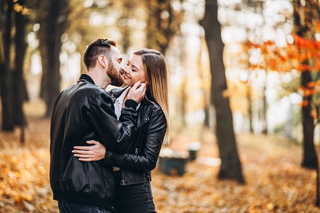 Man and woman hugging and smiling in the background of autumn park.