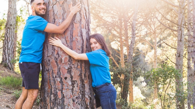 Man and woman hugging tree in lovely forest