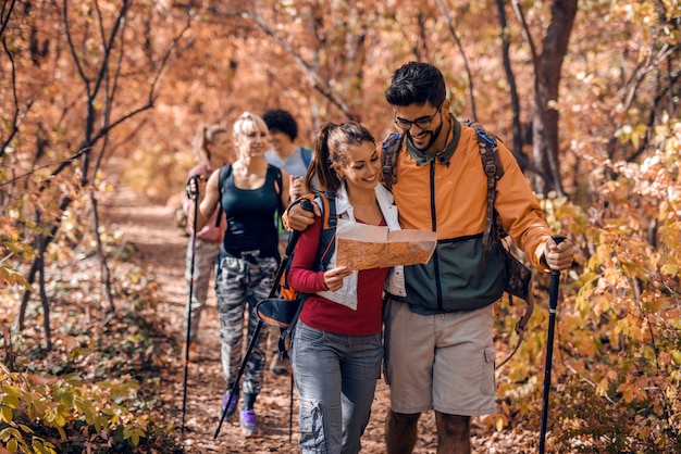 Man and woman hugging and watching map while other hikers following them.