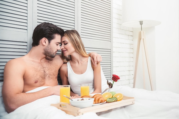 Man and woman hugging with breakfast in the bed at the morning