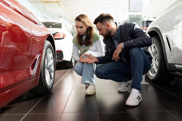 Man and woman inspecting a new car before buying in a car dealership