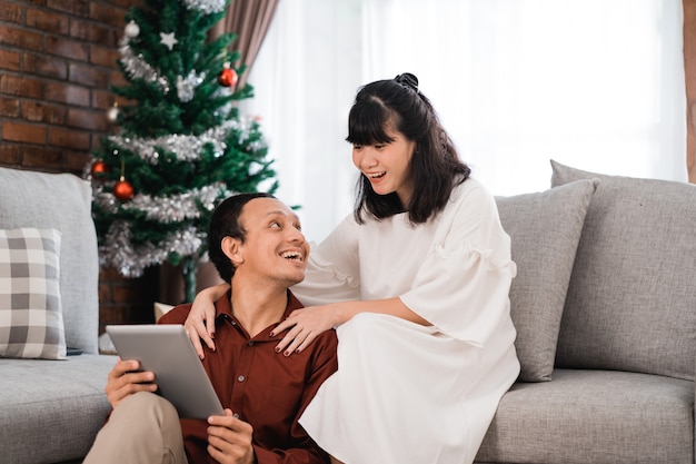 Man and woman in living room together using tablet pc during christmas day