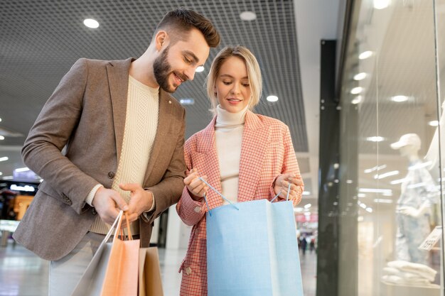 A man and a woman looking in paperbag during shopping in mall