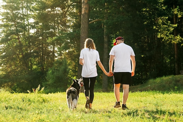 A man and a woman in love walk hand in hand a dog walks next to them and looks at them