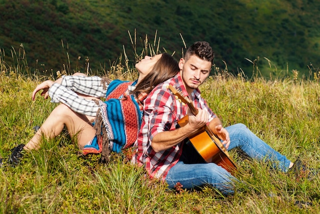 Man and woman playing the guitar and singing in nature