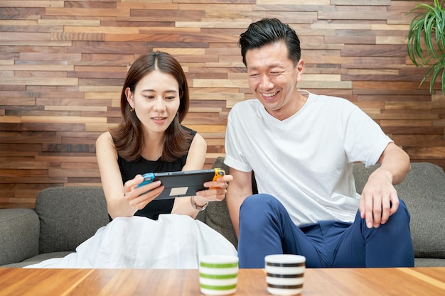 Man and woman playing with portable game machine