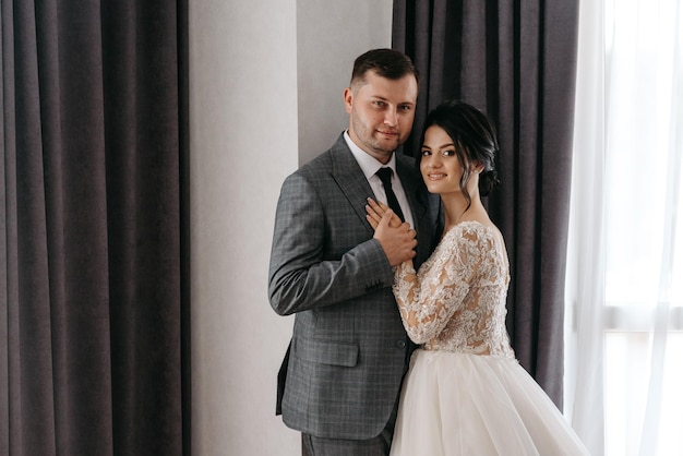 a man and woman pose for a photo in front of a window