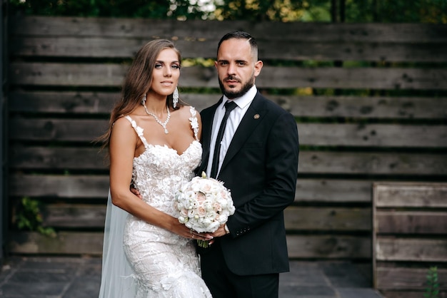 Photo a man and woman pose for a photo in front of a wooden fence