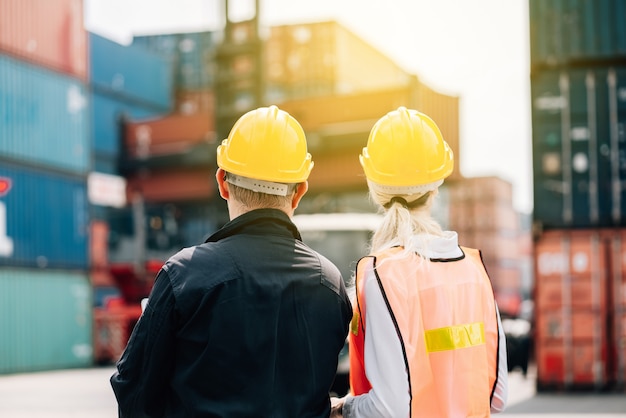 man and woman in safety jumpsuit workwear with yellow hardhat