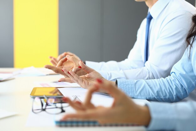 Man and woman sit at table in office and meditate.