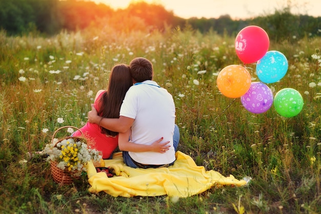 Man and woman sitting in the field and colorful balloons