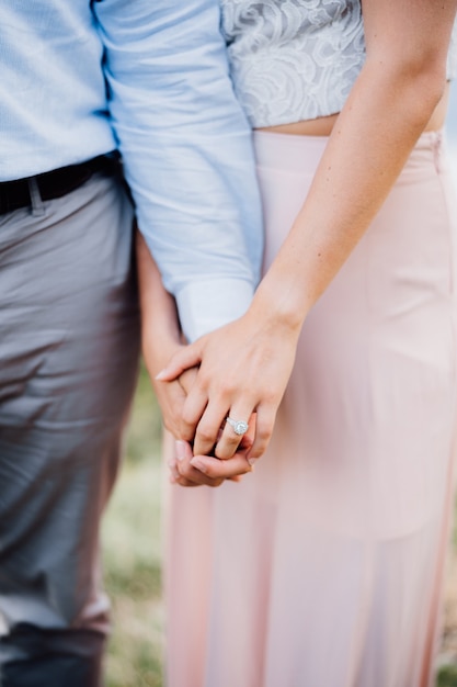 Man and woman stand side by side woman holds man by the hand closeup