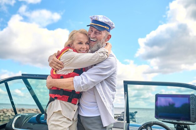 A man and a woman standing on a boat and hugging each other