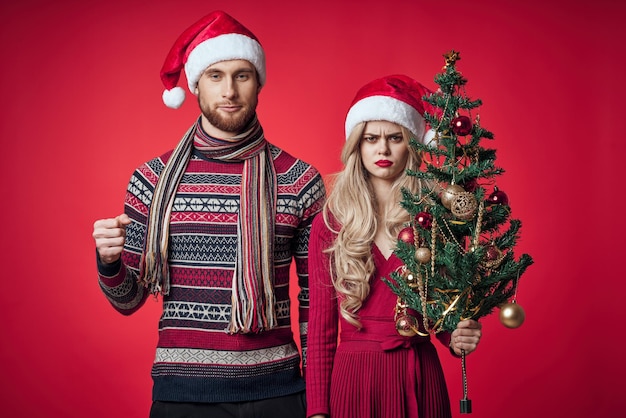 Man and woman standing next to christmas tree toys lifestyle red background