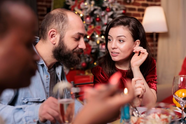 Man and woman talking christmas home party close up, couple chatting at festive dinner table, eating traditional xmas dishes. Friends having conversation, winter holiday celebration