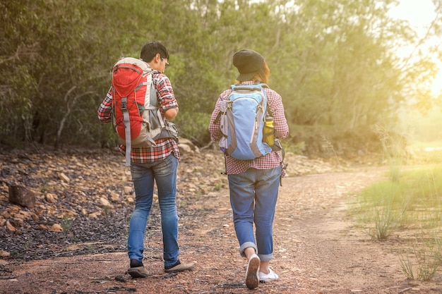 Man and woman walking along have backpack for hiking. 