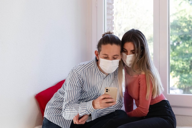 Man and woman wearing a face mask looking at the smartphone