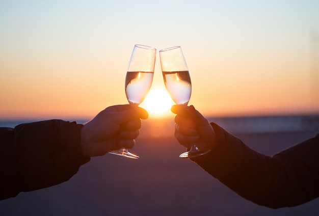 man and woman with glass of wine at sunset