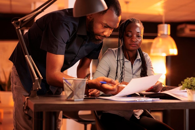 Man and woman working together as business team to create project report with research information and data charts on paperwork. Doing teamwork and analyzing presentation ideas on files.