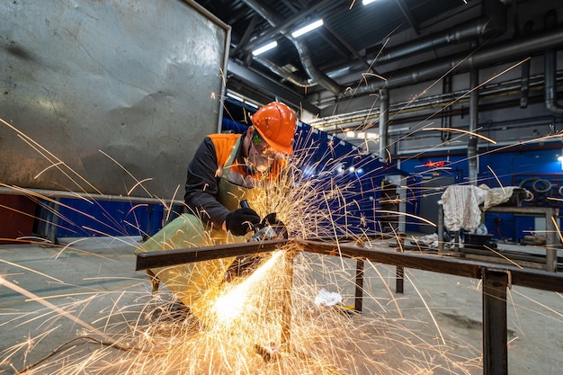 Man work in home workshop garage with angle grinder goggles and construction gloves sanding metal ma