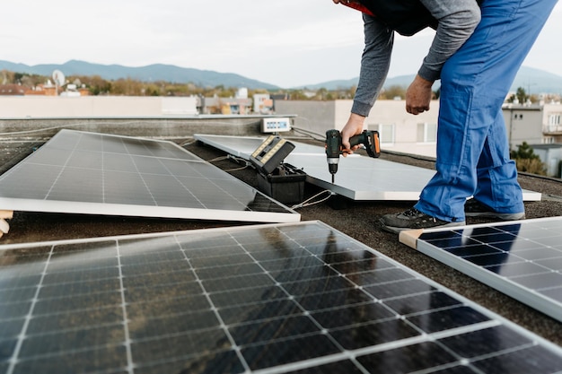 Man worker installing solar photovoltaic panel system using screwdriver alternative energy concept h