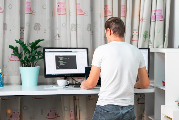 Man working on computer at standing desk at home office Freelancer working from home High standing desk table comfortable for healthy back