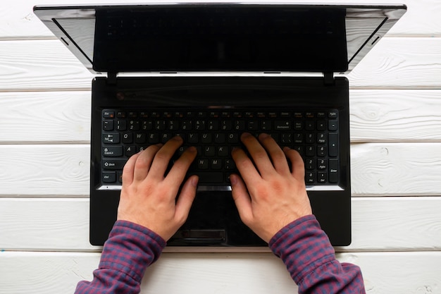 Man working at his laptop on white wooden background