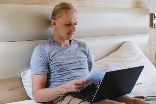 Man working in hotel room on the bed with laptop vacation