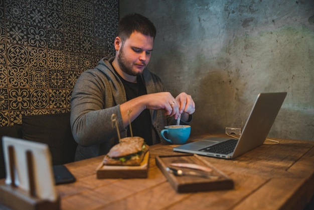 Man working on laptop in cafe breakfast sandwich and coffee