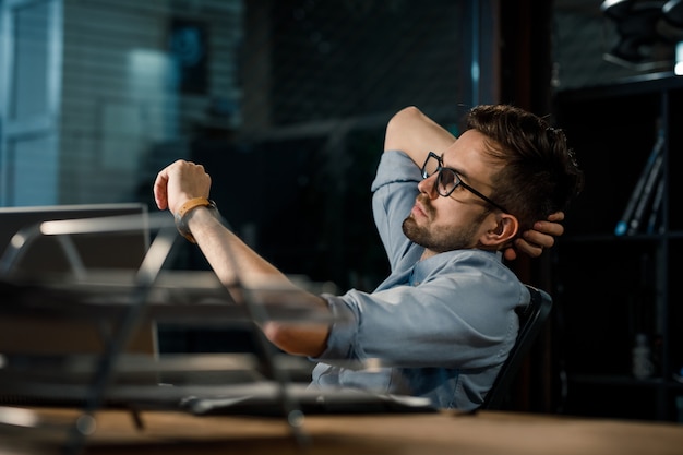 Man working late in office checking time