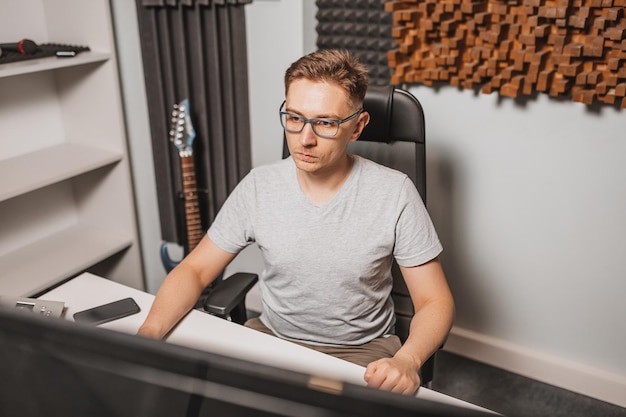 Man working in music studio using computer wearing glasses Sound engineer working and mixing track Programmer watching at display of it while listening music Technology concept