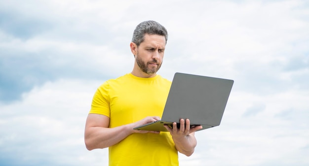 Man working online on computer on sky background