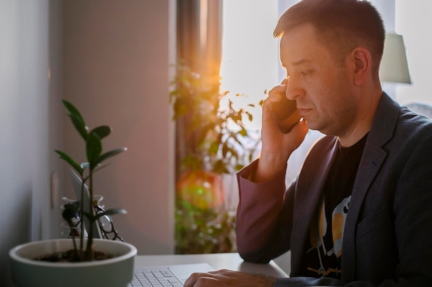 Man working remote job from home office Cheerful freelancer working on laptop talking on the phone