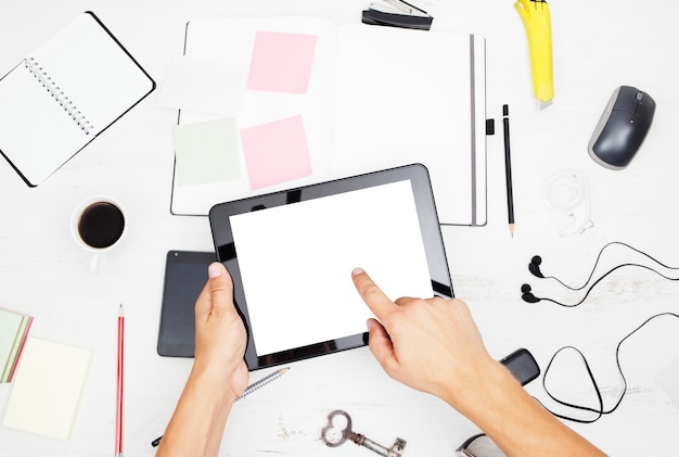 Man working on tablet pc with blank screen notepad and smart phone on white table